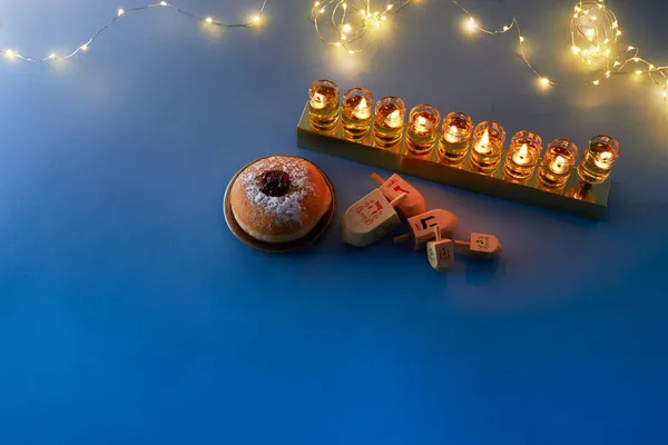 Židovská dovolená Chanuka pozadí s menorah-tradiční svícen, točící se top a kobliha na modrém pozadí — Stock fotografie