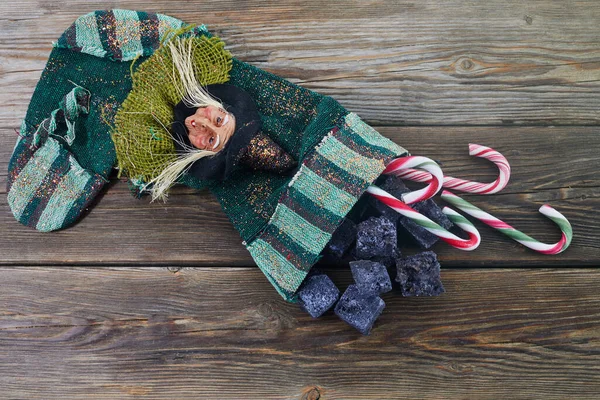 Befana sock with sweet coal and candy on wooden background. Italian Epiphany day tradition. — Stock Photo, Image