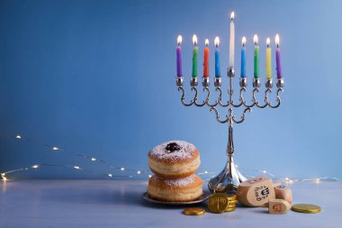 Menora ile Yahudi bayramı Hanuka arkaplanı. Geleneksel şamdan, mavi arka planda Dreidel ve Çörek.