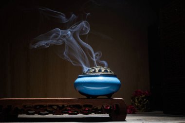 Yanan tütsü çubuklarından çıkan duman lotus tütsü tutacağının üzerinde duruyor.