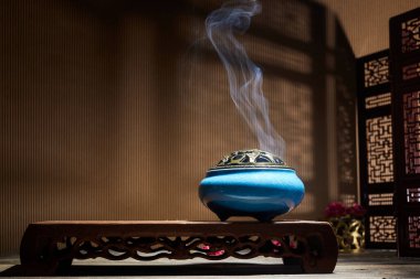 Yanan tütsü çubuklarından çıkan duman lotus tütsü tutacağının üzerinde duruyor.