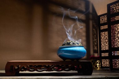 Yanan tütsü çubuklarından çıkan duman lotus tütsü tutacağının üzerinde duruyor.