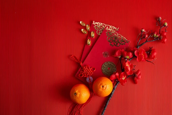 중국의 신년 축제 장식. 오렌지, 나뭇잎, 빨간 꾸러미, 빨간 배경에 있는 자두 꽃. — 스톡 사진