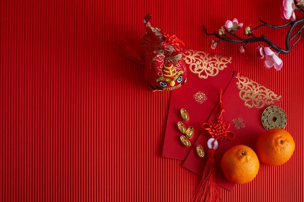 Dekorationen für das chinesische Neujahrsfest. Orange, Blatt, rotes Päckchen, Pflaumenblüte auf rotem Hintergrund. — Stockfoto