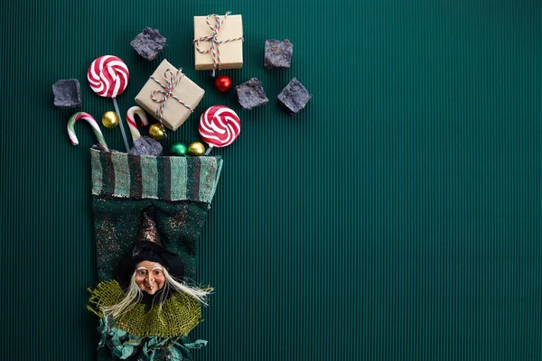 濃い緑色の背景に甘い石炭とキャンディでベファナ靴下。イタリアのエピファニーの日の伝統. — ストック写真