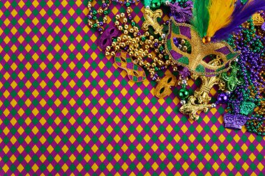 Mardi Gras maskesi çerçevesi ve elmas şekilli arkaplanda renkli Mardi Gras boncukları