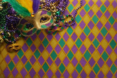 Mardi Gras maskesi çerçevesi ve elmas şekilli arkaplanda renkli Mardi Gras boncukları