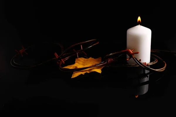 Holocaust memory day. Arbed wire and burning candle on black background — Stock Photo, Image