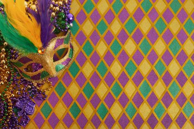 Mardi Gras maskesi çerçevesi ve elmas şekilli arkaplanda renkli Mardi Gras boncukları