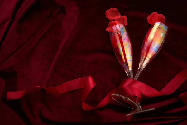 Valentijnsdag achtergrond met champagne bril en rood lint op donkerrode achtergrond — Stockfoto