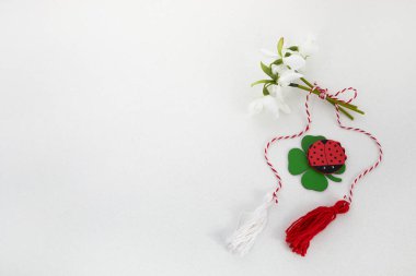 Beyaz zemin üzerinde kırmızı ve beyaz ip ve lalybug ile bir buket kar damlası. Mart ayının ilk kutlamaları Martisor.
