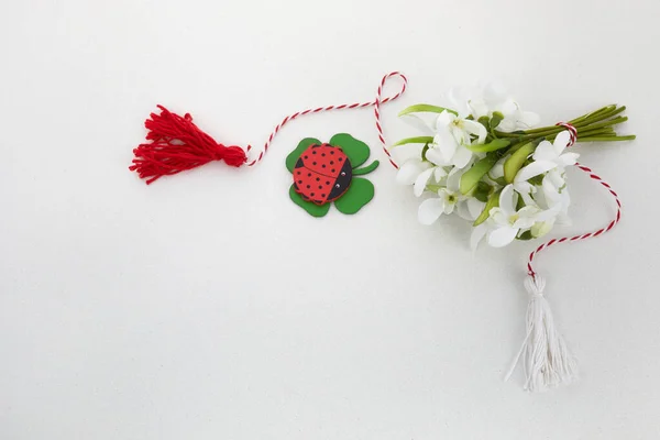 Bouquet di bucaneve su fondo bianco con corda rossa e bianca e lalybug. Prima di marzo celebrazione Martisor. — Foto Stock
