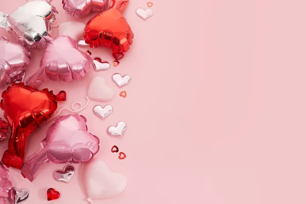 Romantische achtergrond voor bruiloft, Valentijnsdag en verjaardag. Zilveren en roze hartvormige ballonnen, confetti roze metalen liefde hart. — Stockfoto
