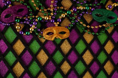 Mardi Gras maskesi çerçevesi ve elmas şekilli arkaplanda renkli Mardi Gras boncukları