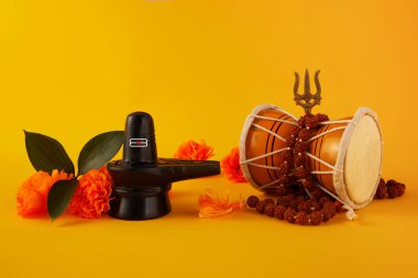 Mutlu Maha Shivaratri tebrik kartı - Shiva Linga çiçeklerle süslenmiş, trishula, damru ve bilva yapraklarıyla. Hindu festivali Shiva Lord 'u kutladı