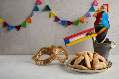 Yahudi bayramı Purim arka planında hamantaschen ya da hamans kulaklı kurabiyeler, karnaval maskesi ve gürültü çıkarıcı