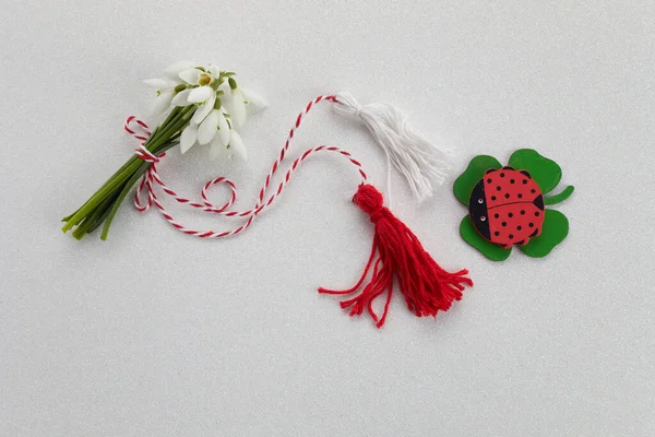 Bouquet of snowdrops on white background with red and white rope and lalybug. First of march celebration Martisor. — Stock Photo, Image