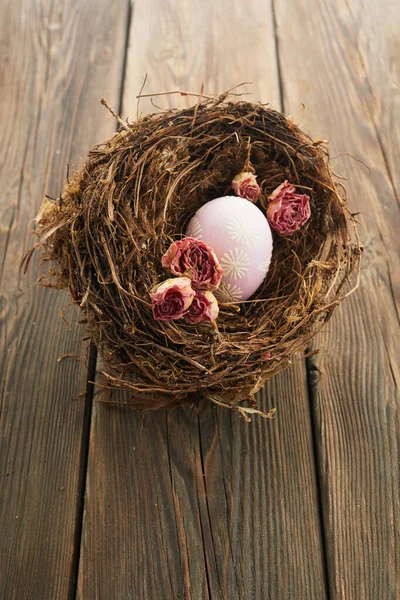 Paskalya yumurtaları, ahşap arka planda bir yuvadaki kuru güller. Minimum konsept. — Stok fotoğraf