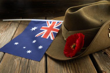 Anzak ordusu, Avustralya Bayrağı ve Poppy ile ahşap arka planda kambur şapka takıyor.