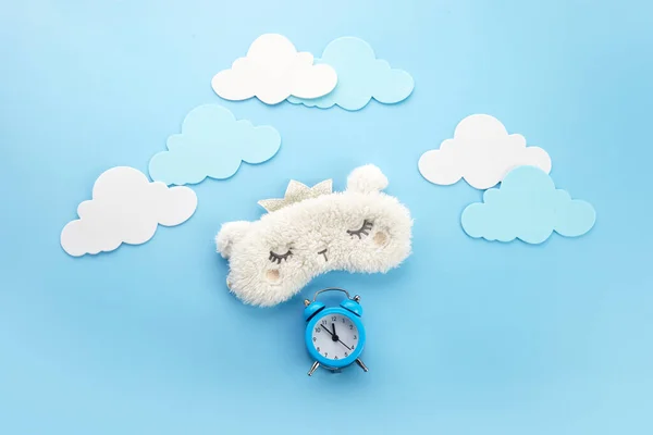 Sleeping eye mask and alarm clock on blue background with clouds. Healthy sleep, rest, insomnia concept — Stock Photo, Image