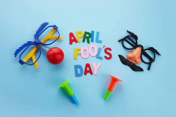 Abril tolos texto do dia e óculos engraçados e chifres no fundo azul — Fotografia de Stock