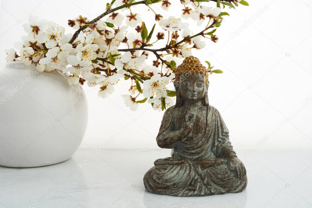 Vesak, Wesak, Buddha birthday. Buddha statue with blossoming cherry on white background. Spa ritual. Mental health and meditation.