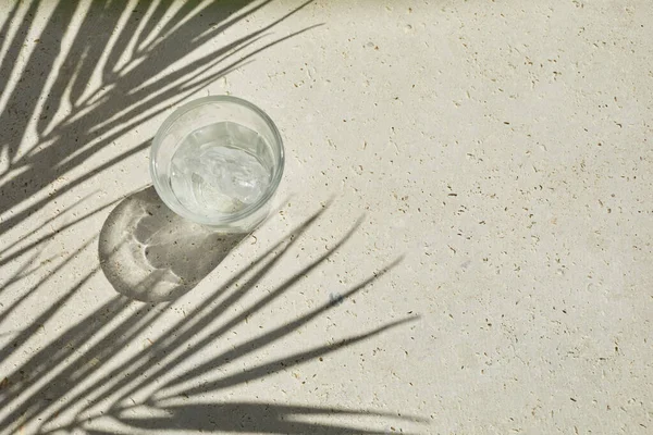 Camdan köpüklü su akımı. Arka planda palmiye yaprağı gölgeleri var. Gün ışığında yaz içkisi. En küçük üst görünüm — Stok fotoğraf