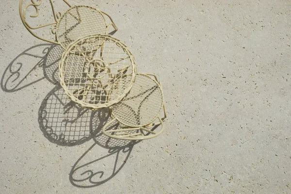 Tisch und Stuhl aus Metall auf Travertin-Stein-Hintergrund. Minimaler Grundriss mit Sonnenschein und hartem Schatten. — Stockfoto