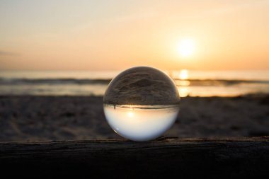 View on a sunset over ocean coast through a glass ball. Selective focus