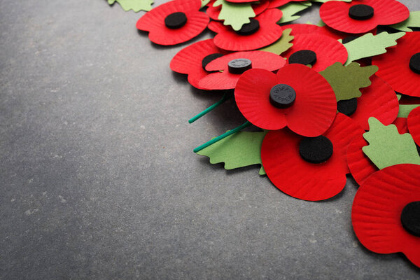 World War remembrance day. Red paper poppies on dark stone background.
