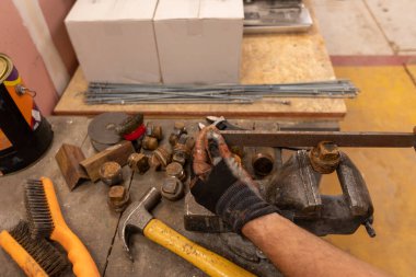 Demirci atölyesinde çalışıyor. Metaller ve çalışma masasıyla.