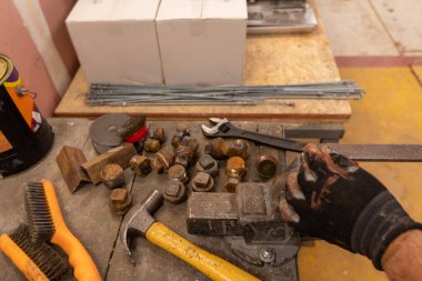 Demirci atölyesinde çalışıyor. Metaller ve çalışma masasıyla.