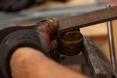 Demirci atölyesinde çalışıyor. Metaller ve çalışma masasıyla.