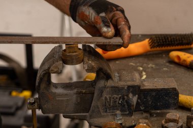 Demirci atölyesinde çalışıyor. Metaller ve çalışma masasıyla.