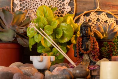 Buda heykeli mihrapta mumlar ve bitkilerle