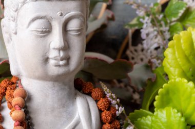 Buda heykeli mihrapta mumlar ve bitkilerle