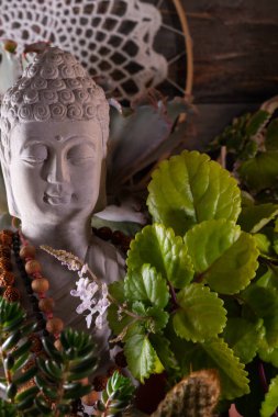 Buda heykeli mihrapta mumlar ve bitkilerle