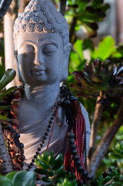 Buda heykeli mihrapta mumlar ve bitkilerle