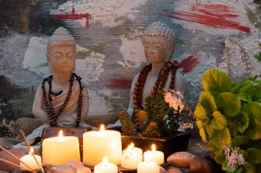 Buda heykeli mihrapta mumlar ve bitkilerle