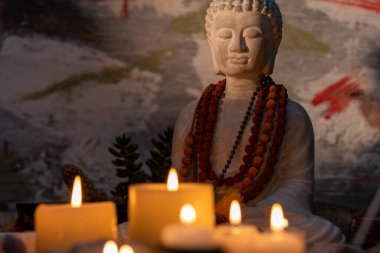 Buda heykeli mihrapta mumlar ve bitkilerle