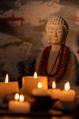 Buda heykeli mihrapta mumlar ve bitkilerle