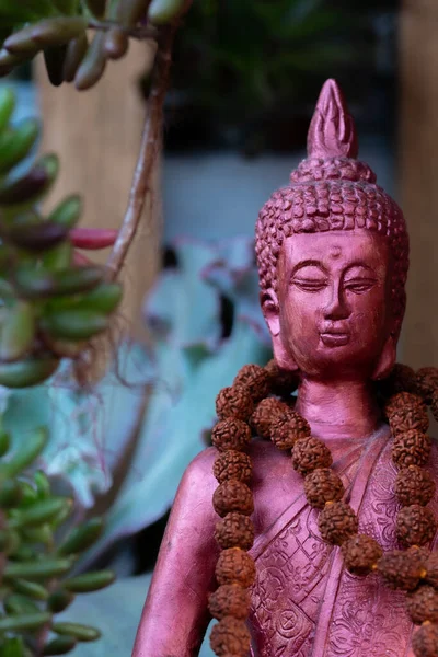 Buda heykeli mihrapta mumlar ve bitkilerle