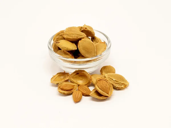 Pile of apricot seeds with bowl — Stock Photo, Image