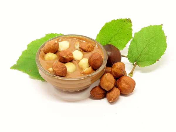 Chocolate in glass bowl with hazelnuts and leafs — Stock Photo, Image