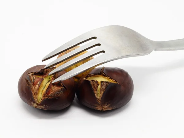 Two roasted chestnuts with fork — Stock Photo, Image