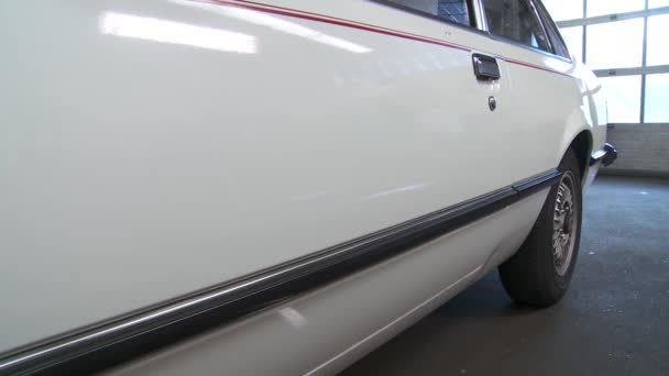 Pan-up view of old white coupe in auto garage — Stock Video