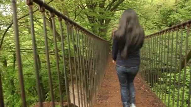 Mujer caminando sobre el puente de cuerda en un bosque — Vídeos de Stock