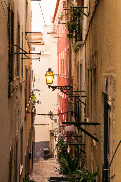 Narrow street in a Portuguese city during the day with a street lamp on