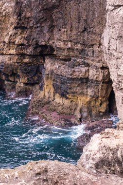 Canlı turkuaz okyanus dalgaları kayalara çarpıyor.