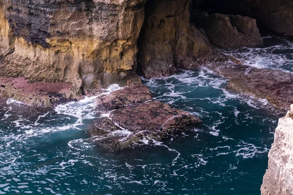 Canlı turkuaz okyanus dalgaları kayalara çarpıyor.